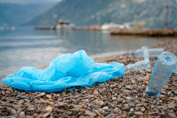 Photo of plastic bag and bottles lying on seacoast.