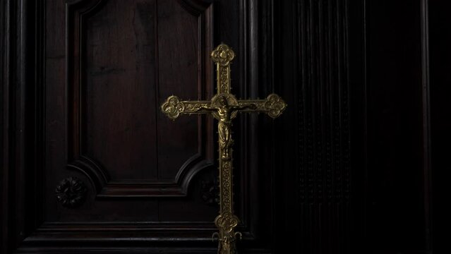 Large golden crucifix inside a dark sacristy. Sacred objects for Christian rituals. Mass tools. Faith, belief in god, image of Jesus on the cross.