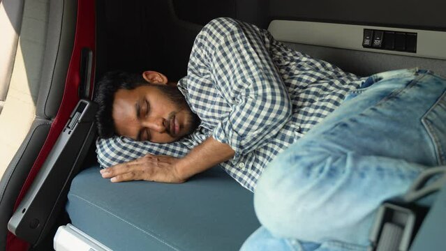 Indian truck driver sleeping in his cabin after working long routes overtime. Lack of sleep