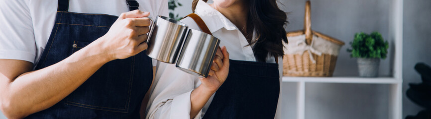 Happy young adult couple making breakfast and drinking coffee together in cozy home kitchen in morning at home. Preparing meal and smiling. Lifestyle, leisure and Love concept.