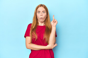 Redhead young woman on blue background having some great idea, concept of creativity.