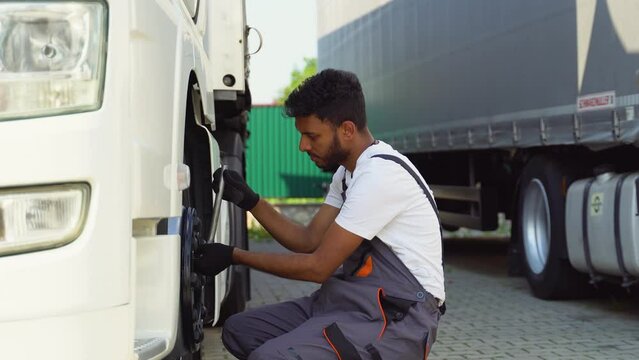 Indian truck driver using socket wrench while changing tire on the road