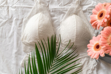 Gentle white lace bra on the bed. Women tender lingerie, underwear. Top view, close up. Flat lay, beauty blog or social media minimal concept. Present for Valentines, Women’s day