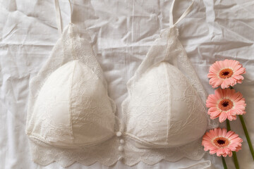 Gentle white lace bra on the bed. Women tender lingerie, underwear. Top view, close up. Flat lay, beauty blog or social media minimal concept. Present for Valentines, Women’s day