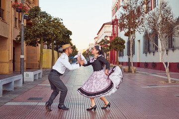 portrait couple dressed in traditional huaso clothes dancing cueca in the street