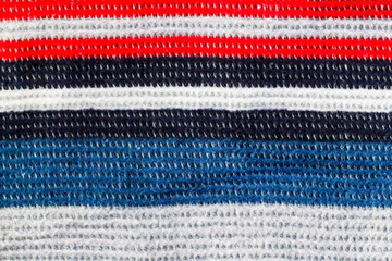 Fototapeta na wymiar Hand knitted wool blanket background with red, blue, white stripes