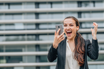 excited happy business woman celebrating looking at mobile phone