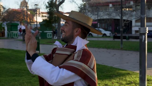 pareja joven con traje de huaso aplaudiendo al ritmo del baile cueca en la plaza de la ciudad
