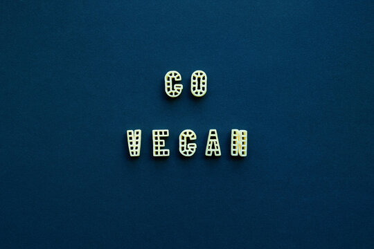 Naklejki Close-up view of ‘Go vegan’ slogan made up of alphabet pasta against dark blue background  