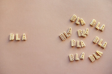 Conceptual photo of multiple words ‘bla’ made up of alphabet pasta against beige background 