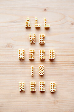 Naklejki Creative remade quote ‘All we need is weed’ written with alphabet pasta letters on wooden table background   