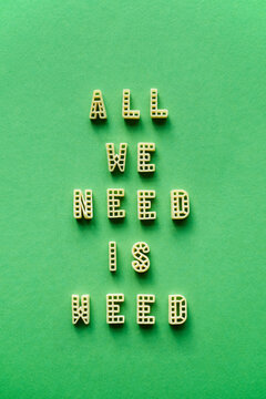 Naklejki Alphabet pasta forming creative remade quote ‘All we need is weed’ against green background 