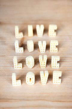 Row of words &lsquo;love&rsquo; written with alphabet pasta on wooden table 