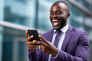 Man wearing purple suit is captured smiling as he looks at his cell phone. This image can be used to depict modern communication, technology, and professional attire.