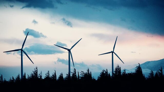Time lapse of dark clouds moving over wind turbines in the evening. Power generator plant for renewable green energy production on hill. Occitanie, France.