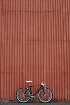 Retro bicycle with blue rims parked outdoors against brown wall background   