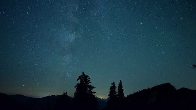 Zeitrafferaufnahme vom Sternenhimmel mit der Milchstra&szlig;e in den Chiemgauer Alpen mit Wald und dem Rauschberg rechts, Bayern, Deutschland