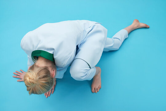 Conceptual shot of unrecognizable blond young woman in unnatural pose on vivid blue background, high angle view  
