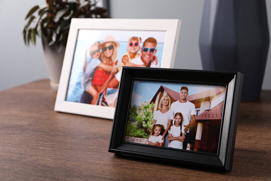Frames with family photos on wooden table indoors