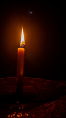 a burning candle against a dark background
