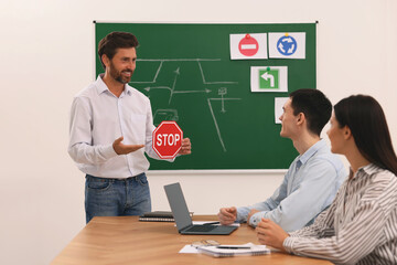 Teacher showing Stop road sign to audience during lesson in driving school
