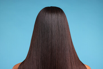 Fototapeta premium Woman with healthy hair after treatment on light blue background, back view