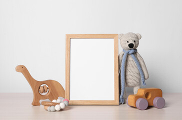 Empty square frame and different toys on white wooden table