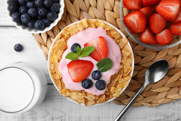Delicious crispy cornflakes, yogurt and fresh berries served on white wooden table, flat lay. Healthy breakfast