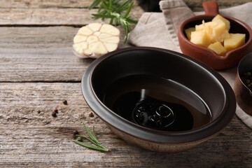 Bowl of balsamic vinegar with oil on wooden table, closeup. Space for text