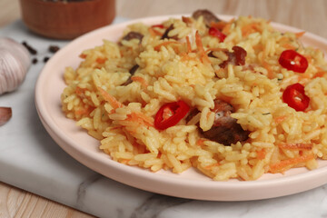 Delicious pilaf with meat on wooden table, closeup