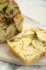 Freshly baked pesto bread on white marble table, closeup