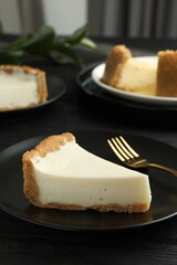 Piece of tasty vegan tofu cheesecake and fork on black wooden table, space for text