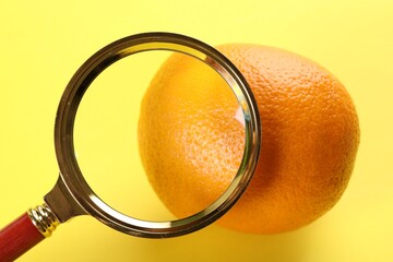 Cellulite problem. Orange and magnifying glass on yellow background