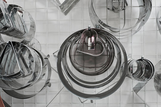 Baking forms of different shapes and sizes hanging in confectionery kitchen, close-up view 