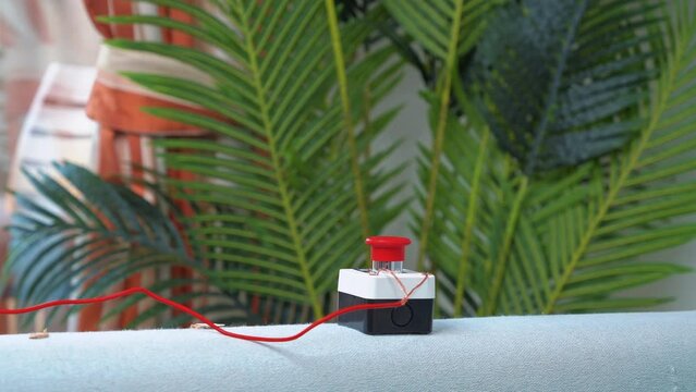 Close-up of red button with wire, detonator of toy children bomb explodes, splinters are pouring in cozy apartment Animation party, birthday, entertainment experiences, surprises, dangerous tricks