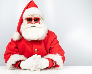 Portrait of santa claus sitting with his arms folded at a white table. 