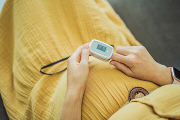 Pregnant woman with pulse oximeter on finger. Doctor measuring oxygen saturation level while...