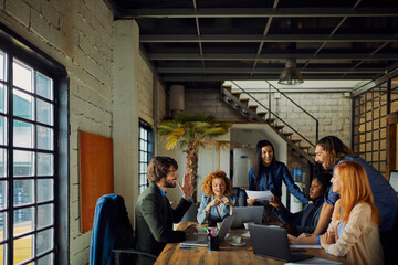 Young and diverse group of coworkers working on a project and having a meeting in a startup company...