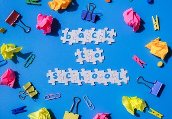 BACK TO SCHOOL message inscription text on white puzzles on creative colorful blue background...
