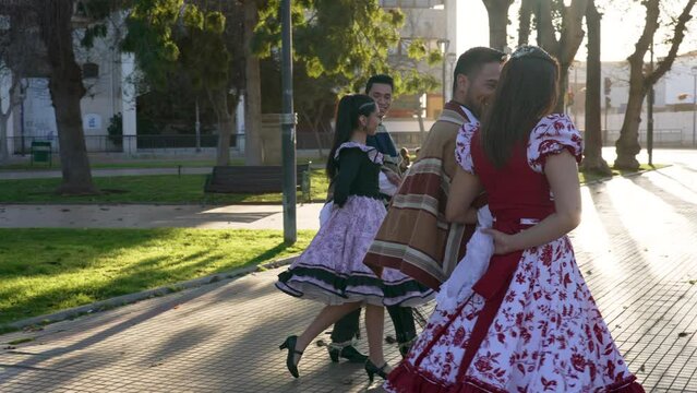 men in huaso costumes lead the women by the arm to dance the cueca in the street
