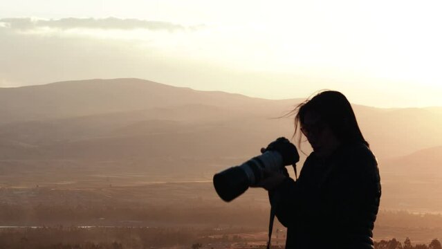 Video of a silhouette of a photographer at a sunset in the mountains. Concept of lifestyles, professions and nature.