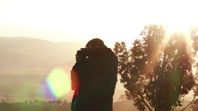 Video of photographer taking pictures on a mountain and sunset. Concept of people and travel.