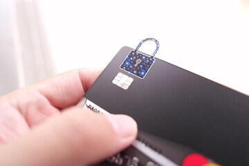 Close up of man hand holding credit or debit card with padlock, black credit card with protection...