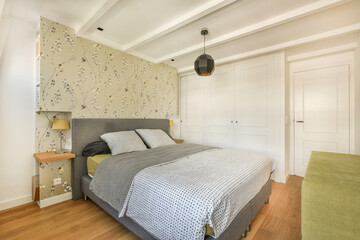 a bedroom with a bed, chair and wallpapered walls in the room behind it is a white door