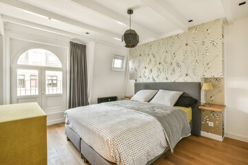 a bedroom with wood flooring and white walls, along with a bed in the room has a patterned headboard on the wall