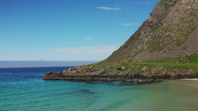 Revealing drone shot starting on rocky coastline then revealing the beautiful turquoise water and private Horseid Beach. Northern side of Moskenes&oslash;y, in the western part of Lofoten