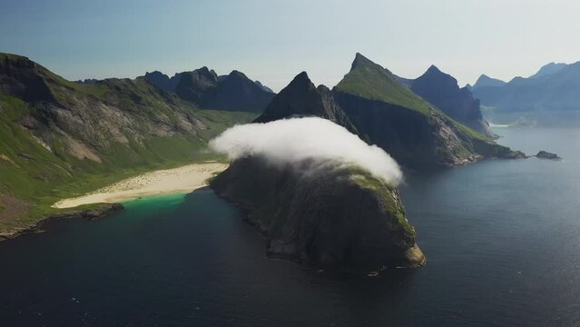 Cinematic wide rotating drone shot of Horseid Beach with turquoise blue water, clouds moving over cliffs. Northern side of Moskenes&oslash;y, in the western part of Lofoten
