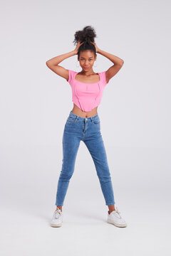 Effortlessly chic: Woman's studio pose captures her in a pink shirt and blue jeans, epitomizing modern style.