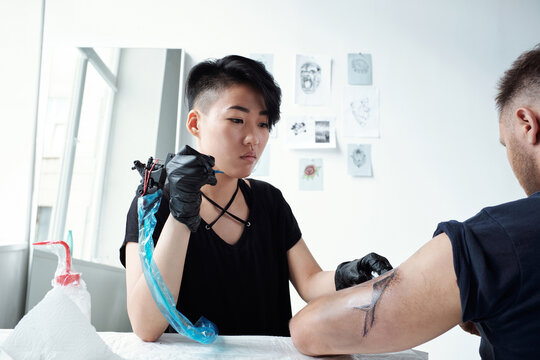 Artist with tattoo machine inspecting new picture