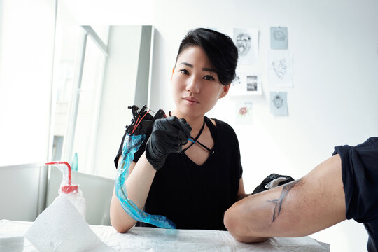 Attractive female tattoo artist at work